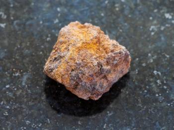 macro shooting of natural mineral rock specimen - rough limonite (iron ore) stone on dark granite background