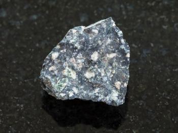macro shooting of natural mineral rock specimen - rough Andesite stone on dark granite background