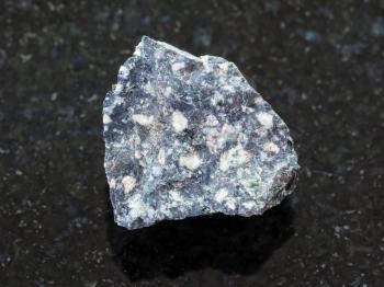 macro shooting of natural mineral rock specimen - raw Andesite stone on dark granite background