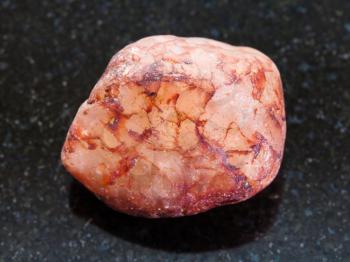 macro shooting of natural mineral rock specimen - pebble of quartz stone on dark granite background