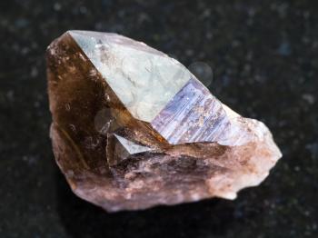 macro shooting of natural mineral rock specimen - rough crystal of smoky quartz gemstone on dark granite background