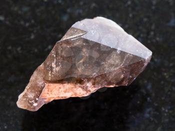 macro shooting of natural mineral rock specimen - crystal of smoky quartz gemstone on dark granite background