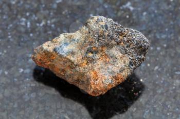 macro shooting of natural mineral rock specimen - rough Psilomelane (manganese ore) stone on dark granite background