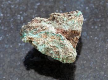 macro shooting of natural mineral rock specimen - raw Malachite (copper ore) stone on dark granite background