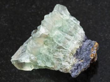 macro shooting of natural mineral rock specimen - raw crystalline fluorite gemstone on dark granite background from Usugli region of Zabaykalsky Krai in Russia