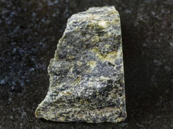 macro shooting of natural mineral rock specimen - raw Diopside stone on dark granite background from Kovdor region, Kola Peninsula in Russia