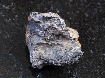macro shooting of natural mineral rock specimen - ilmenorutile (Nb-bearing rutile) stone on dark granite background from South Ural Mountains, Russia