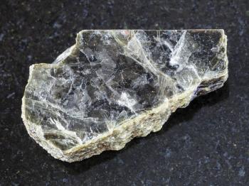 macro shooting of natural mineral rock specimen - raw muscovite mica stone on dark granite background from Pirtima mine, Karelia, Russia
