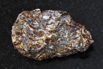 macro shooting of natural mineral rock specimen - rough Titanite stone on dark granite background from Khibiny Mountains, Kola Peninsula, Russia