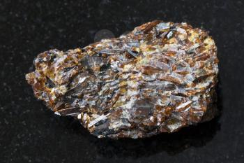 macro shooting of natural mineral rock specimen - raw Titanite stone on dark granite background from Khibiny Mountains, Kola Peninsula, Russia