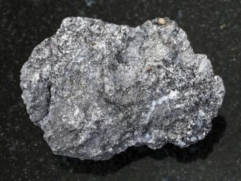 macro shooting of natural mineral rock specimen - rough Graphite stone on dark granite background from Bogotol region of Eastern Sayan Mountains, Russia