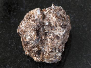 macro shooting of natural mineral rock specimen - rough Phlogopite stone on dark granite background from Tajikistan