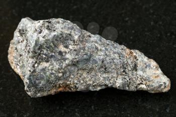 macro shooting of natural mineral rock specimen - rough biotite nepheline syenite stone on dark granite background