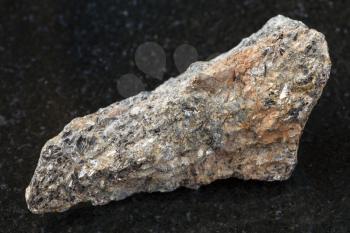 macro shooting of natural mineral rock specimen - raw biotite nepheline syenite stone on dark granite background