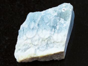 macro shooting of natural mineral rock specimen - rough blue Violane stone on dark granite background from Qurama Mountains in Uzbekistan