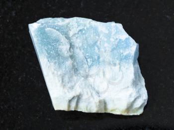 macro shooting of natural mineral rock specimen - raw blue Violane stone on dark granite background from Qurama Mountains in Uzbekistan