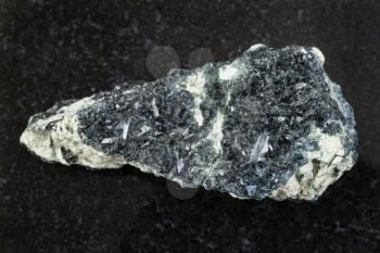 macro shooting of natural mineral rock specimen - raw crystal of hornblende on amphibole - carbonate stone on dark granite background from Korshunovskoe mine of Irkutsk region of Russia