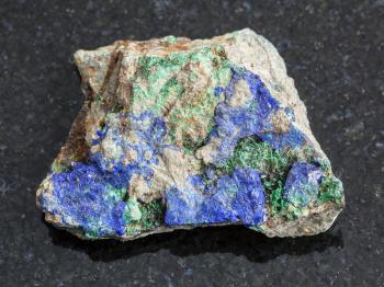 macro shooting of natural mineral rock specimen - blue Azurite and green Malachite on rough stone on dark granite background from Ural Mountains, Russia