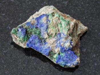 macro shooting of natural mineral rock specimen - blue Azurite and green Malachite on raw stone on dark granite background from Ural Mountains, Russia