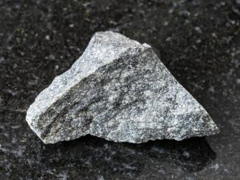 macro shooting of natural mineral rock specimen - raw olivinite stone on dark granite background from Kovdor region, Kola Peninsula, Russia