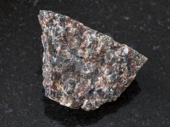 macro shooting of natural mineral rock specimen - rough spreusteined urtite stone on dark granite background from Khibiny Mountains, Kola Peninsula, Russia