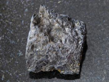 macro shooting of natural mineral rock specimen - rough Bituminous coal stone on dark granite background