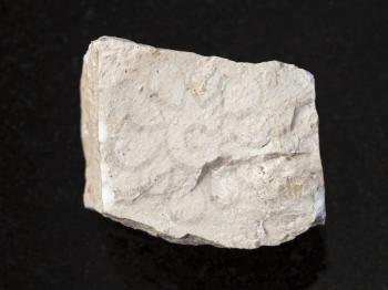 macro shooting of natural mineral rock specimen - rough chemical limestone stone on dark granite background
