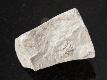 macro shooting of natural mineral rock specimen - raw chemical limestone stone on dark granite background