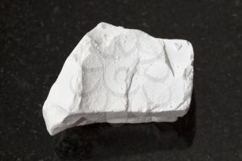 macro shooting of natural mineral rock specimen - raw chalk stone on dark granite background