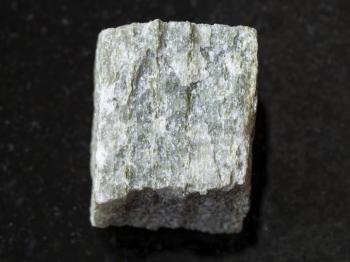 macro shooting of natural mineral rock specimen - raw quartz-mica schist stone on dark granite background