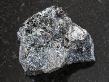 macro shooting of natural mineral rock specimen - raw Magnetite ore on dark granite background from Kovdor, Karelia, Russia
