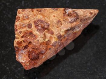 macro shooting of natural mineral rock specimen - rough bauxite ore on dark granite background from Ukraine