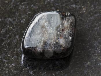macro shooting of natural mineral rock specimen - tumbled anthophyllite gemstone on dark granite background from Tirol, Austria