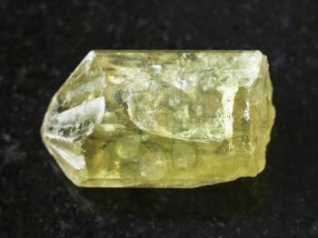 macro shooting of natural mineral rock specimen - raw crystal of yellow apatite gemstone on dark granite background from Mexico