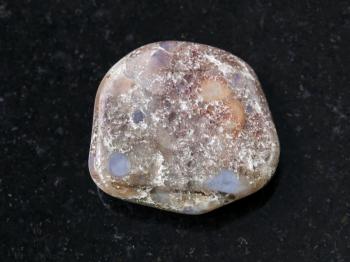 macro shooting of natural mineral rock specimen - polished porphyry gemstone on dark granite background