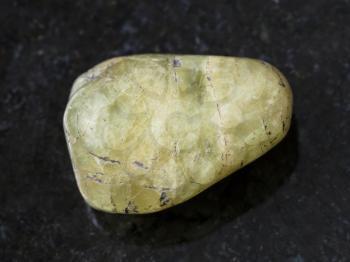 macro shooting of natural mineral rock specimen - polished green beryl gem stone on dark granite background