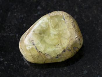 macro shooting of natural mineral rock specimen - tumbled green beryl gem stone on dark granite background