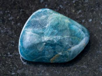 macro shooting of natural mineral rock specimen - polished green blue Apatite gemstone on dark granite background from Araguaia mine, Brazil