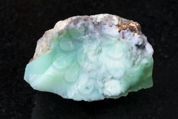 macro shooting of natural mineral rock specimen - rough crystal of Chrysoprase gemstone on dark granite background from Kazakhstan