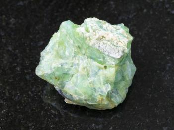 macro shooting of natural mineral rock specimen - raw crystal of chrysopal gemstone on dark granite background from Pstan mine, Kazakhstan