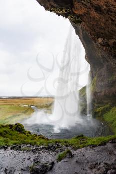 travel to Iceland - wet path inside of Seljalandsfoss waterfall of Seljalands River in Katla Geopark on Icelandic Atlantic South Coast in september