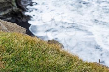 travel to Iceland - green grass on edge of cliff near Vik I Myrdal village on Atlantic South Coast in Katla Geopark in september