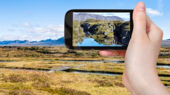 travel concept - tourist photographs Silfra fissure in rift valley of Thingvellir national park in Iceland in september on smartphone