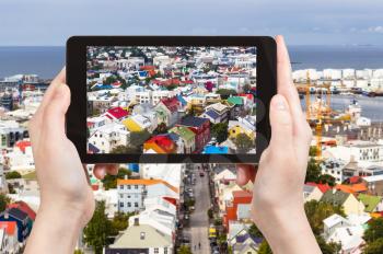 travel concept - tourist photographs residential houses in Reykjavik city in Iceland in september on tablet
