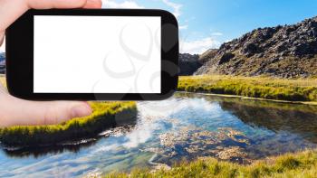 travel concept - tourist photographshot river in Landmannalaugar area of Fjallabak Nature Reserve in Highlands region of Iceland in autumn on smartphone with cut out screen for advertising logo
