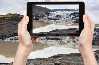 travel concept - tourist photographs melting water and Solheimajokull glacier (South glacial tongue of Myrdalsjokull ice cap) in Katla Geopark in Iceland in september on tablet