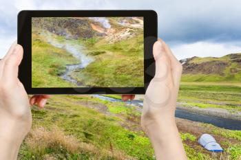 travel concept - tourist photographs valley of Varma river in Hveragerdi Hot Spring River Trail area in Iceland in september on tablet