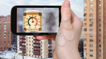 travel concept - tourist photographs outdoor thermometer in sunny winter day in Moscow city on smartphone
