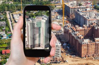 travel concept - tourist photographs construction site in Krasnogorsk district of Moscow Region in Nakhabino village in Russia in summer on smartphone