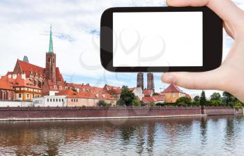 travel concept - tourist photographs Churches and Cathedral on Ostrow Tumski in Wroclaw city in Poland from Oder River in autumn on smartphone with cut out screen for advertising logo